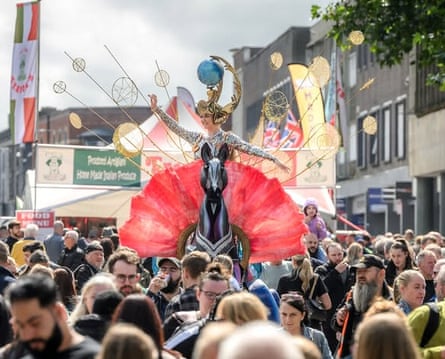 very busy street with woman in fancy dress standing above the crowd