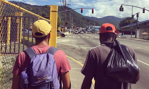 two men walking along a street in Kingston, Jamaica, pictured from behind
