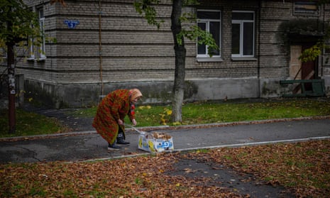 An elderly woman collects bits of cardboard and paper to burn for heating in Lyman, Donetsk region, after the recapture of the area from the Russian forces.