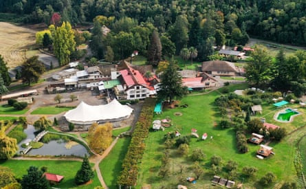 An aerial view of white-painted building with red roofs and a large expanse of bright green grass.