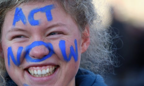 A protestor with the writing 'Act now" on her face takes part in a protest march