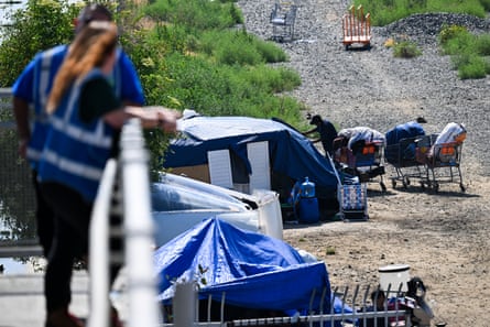 a woman in a reflective vest looks out at a person standing outside a tent