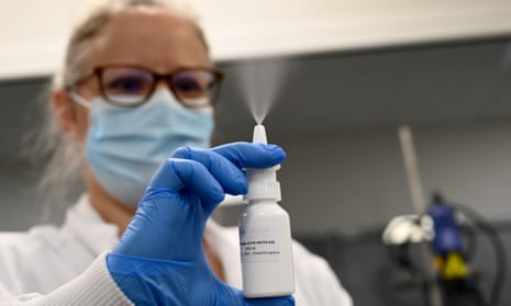 A woman spraying a nasal spray in a lab.