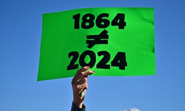 A hand holding a sign with 1864 and 2024 written on it