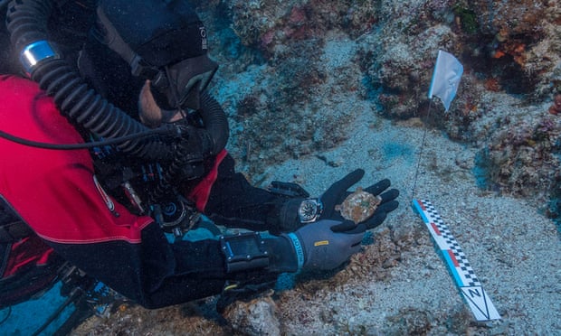 A diver holds a bronze disc discovered during the 2017 underwater excavations at Antikythera, Greece