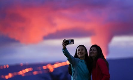Ingrid Yang, left, and Kelly Bruno, both of San Diego, take a photo in front of lava erupting from Hawaii’s Mauna Loa volcano on 30 November.