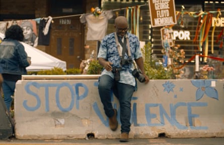 The photographer sits on a concrete barrier which has been spray-painted with “stop the violence”