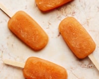 Six orange ice lollies on a marble surface.