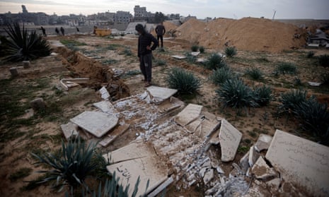 Palestinians inspect graves damaged graves after a raid by Israeli tanks on a cemetery in Khan Younis on Wednesday.
