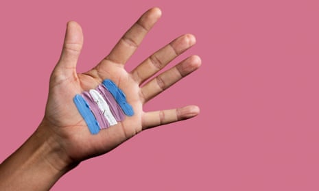 closeup of the palm of the hand of a young Caucasian person with a transgender flag painted in it, against a pink background