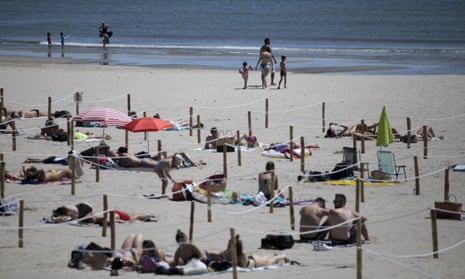 Sunbathers lie in an area marked by cordons of ropes and wooden stakes to enforce social distancing measures in La Grande Motte, southern France.