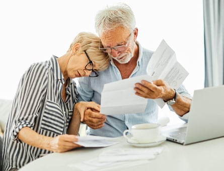 A couple with paper document retirement paperwork and a laptop