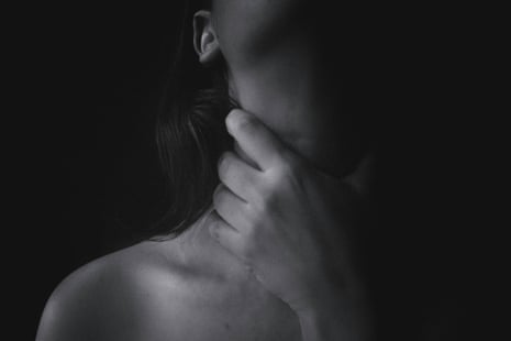 Woman with male hand around her neck against black background