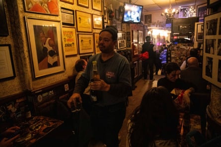 a man carries multiple drinks between tables in a bar