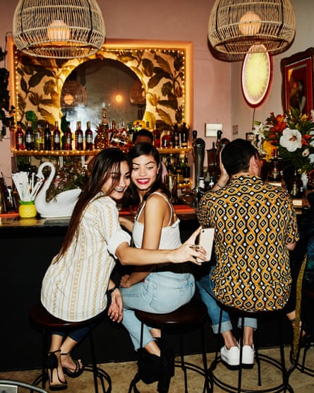 female friends take a selfie while sitting at a bar