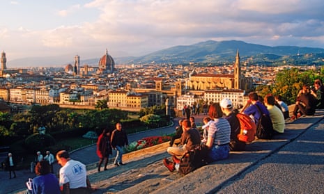 Tourists resting on steps at Piazzale Michelangelo above Florence’s Arno river at sunset