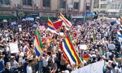 Protesters wave Druze five-coloured flags in the crowds during a protest in the city of Suwayda.