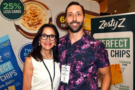 A female and a man guidelines astatine a business convention successful beforehand of signage for Zesty Z pita chips