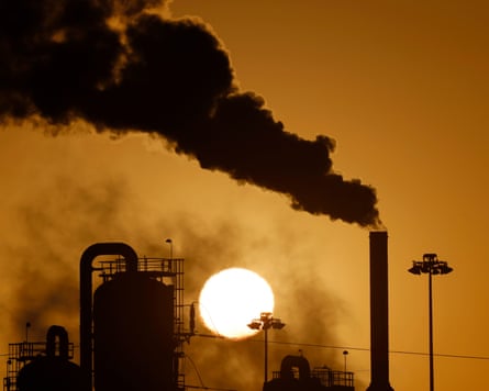 Pollution rises from a geothermal power plant in front of the sun, in California.