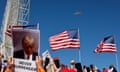 A group of people holding cell phones, American flags and signs supporting Donald Trump look up at the sky, where the former president's airplane flies over.
