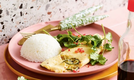 A plated omelette with a mound of rice next to it and herbs on top