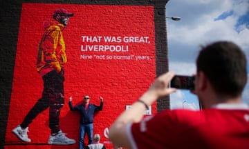 A Liverpool supporter poses in front of a mural near Anfield marking the end of Jürgen Klopp’s time at the club.