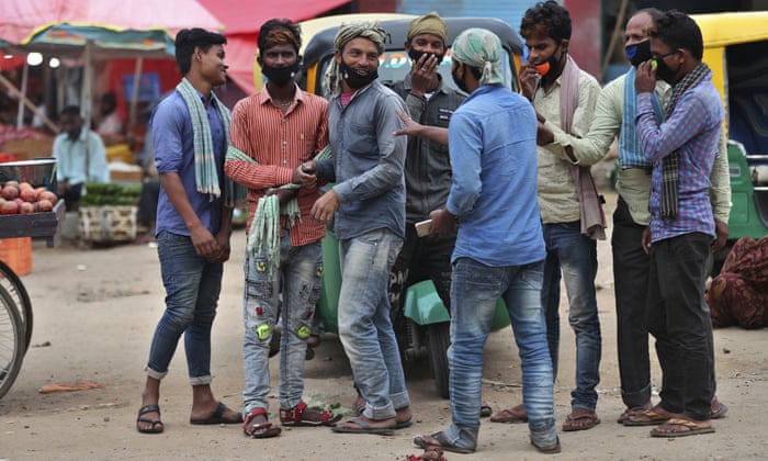 Daily wage labourers wearing face masks as a precaution against the coronavirus stand together as they wait for work at a wholesale market in Bengaluru, India, Thursday, 24 September 2020.