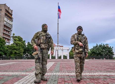Russian servicemen patrol a square with the Russian national flag in central Melitopol