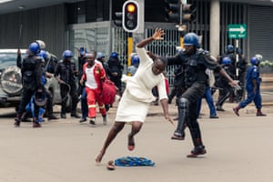 A policeman tackles a woman with his boot in Harare, Zimbabwe