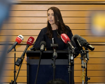 Jacinda Ardern stands at a lectern behind microphones