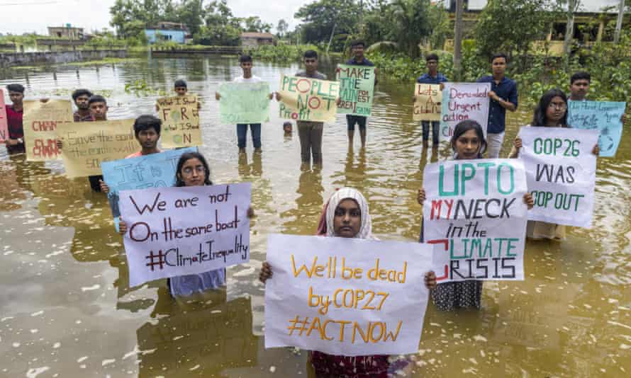 Des militants du climat au Bangladesh se tiennent dans l'eau et tiennent des pancartes 