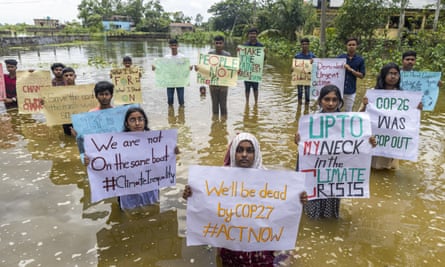 Bangladesh climate activists stand in water and hold placards 