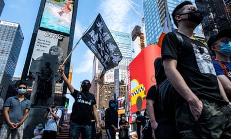 Protester supporting Hong Kong’s pro-democracy movement wearing protective mask holds a flag as they attend the Delay No More, Democracy march in Times Square