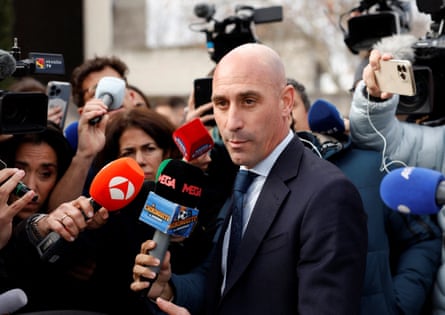 Luis Rubiales surrounded by microphones outside court.
