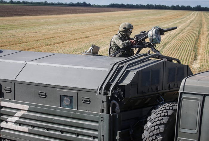 An armed Russian serviceman on a military vehicle keeping watch in a field near Melitopol, in an occupied area of Zaporizhia.