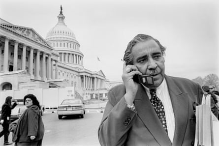 black and white picture of a man speaking into a flip phone in front of the capitol