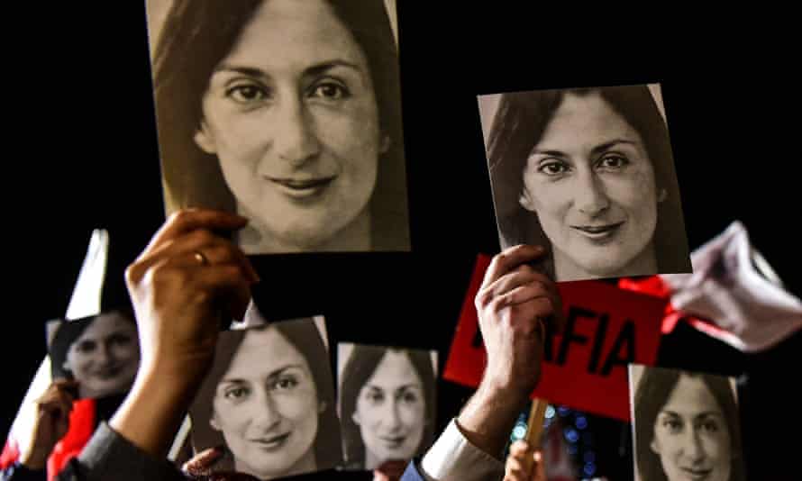 People holding signs reading 'Mafia Government' and photos of Daphne Caruana Galizia during a protest called by her family and civic movements in front of the Prime Minister's office in Valletta, Malta in 2019.
