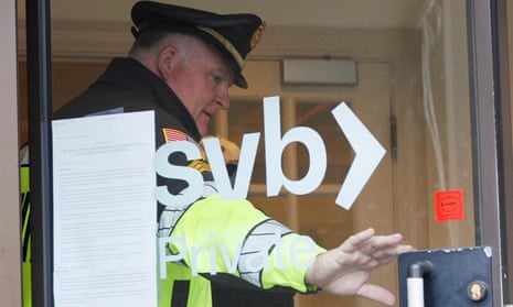 A police officer holds the door open for a customer at Silicon Valley Bank in Wellesley, Massachusetts