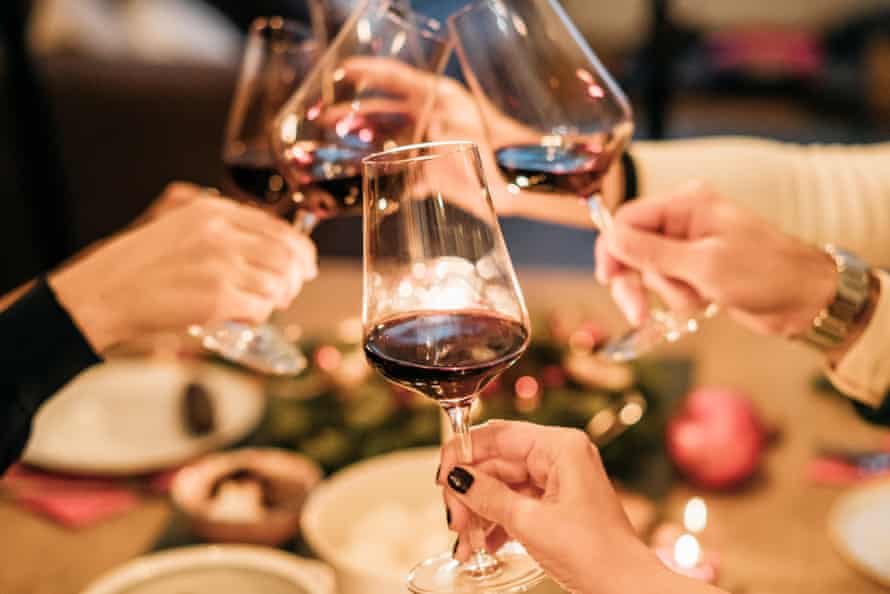 Friends toasting wine glasses at dining tableHappy male and female friends toasting wine glasses at dining table during Christmas