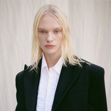 A model in a jacket ands collared shirt with simple loose blonde shoulder-length hair