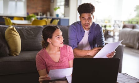 Models release: Young couple discussing over house expense bills and laptop in living room