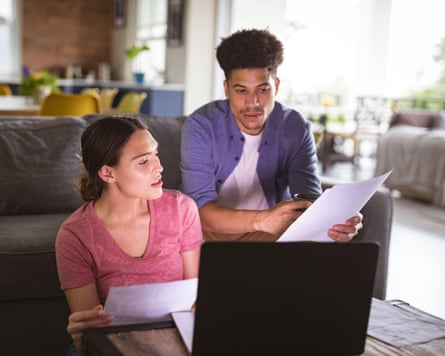 Young couple discussing bills with laptop in living room