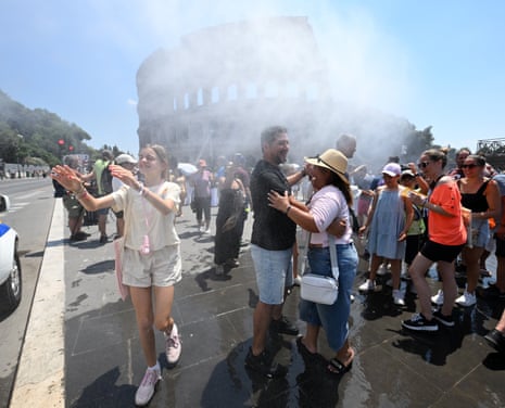 People cool off near a misting equipment near the Colosseum amid a heatwave in Rome, Italy.