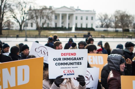 a person holds a sign that reads 'defend our immigrant communities'