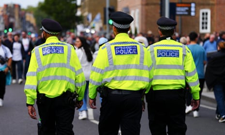 Three Met police officers walking down a crowded road