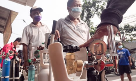 People wait in line to refill their oxygen tanks at a filling station in Jakarta