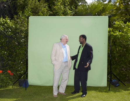 David Attenborough and Ben Okri standing together in front of a green background with bushes behind, in 2009.