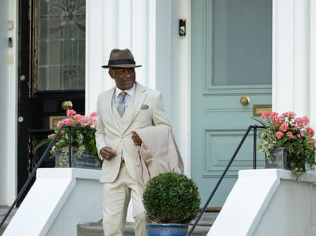 Lennie James in Mr Loverman. He is wearing a pale suit and hat walking down the steps to a house.