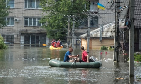 People sail on boats in a flooded street in Kherson on Thursday