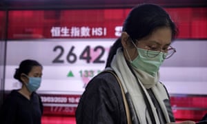 People walk past an electronic board showing Hong Kong share index outside a local bank